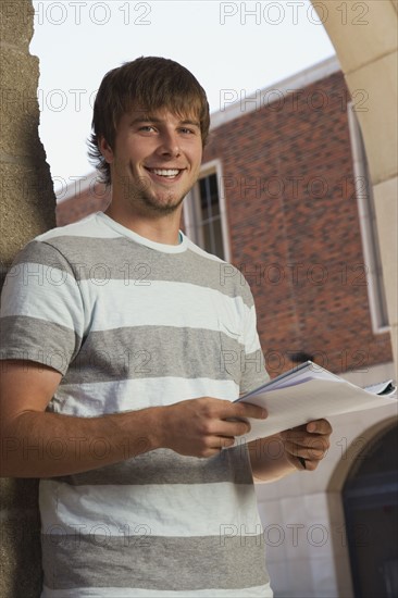 Happy teenage boy holding schoolwork. Photo : Stewart Cohen