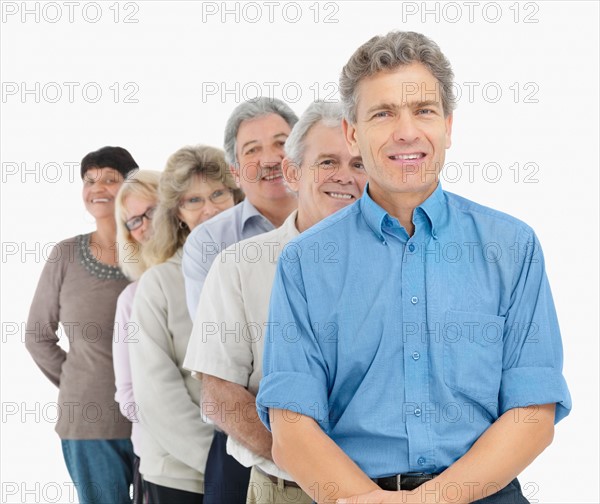 A group of smiling people standing in a line. Photo : momentimages