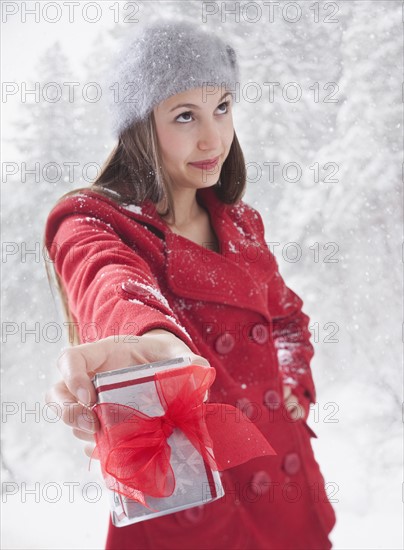 Woman grudgingly holding out a Christmas gift. Photo : Mike Kemp