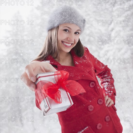 Smiling woman holding out a Christmas gift. Photo : Mike Kemp