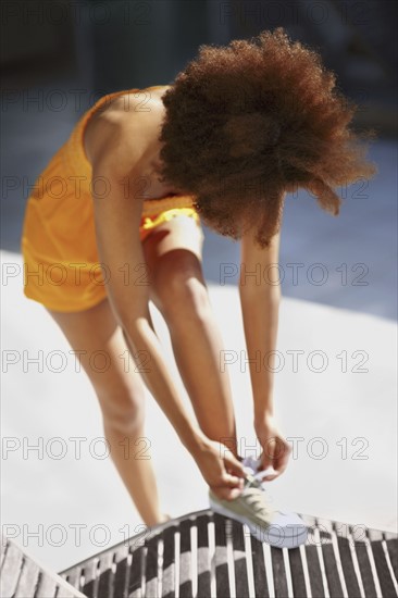 Woman tying her shoelace. Photo : momentimages