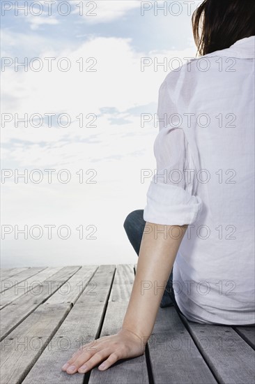 Woman sitting on dock. Photo : momentimages