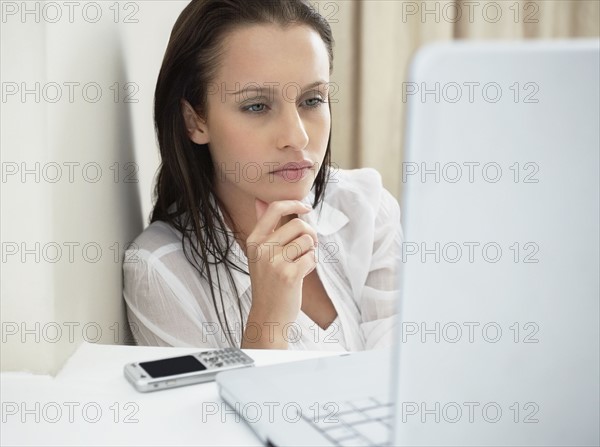 Woman deep in thought while looking at laptop. Photo : momentimages