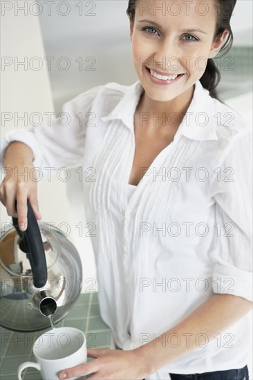 Woman pouring hot water from kettle. Photo : momentimages