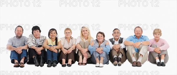 A group of people sitting on the floor in a row. Photo : momentimages
