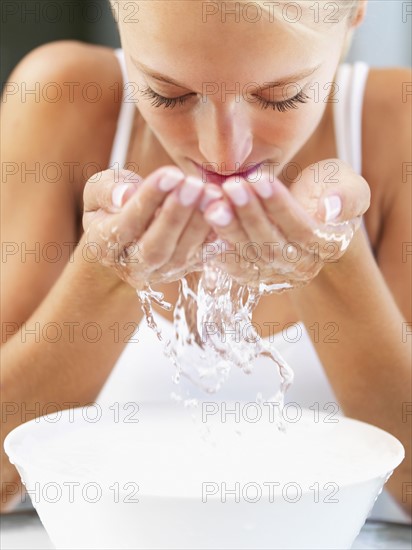 Woman splashing water on her face. Photo : momentimages