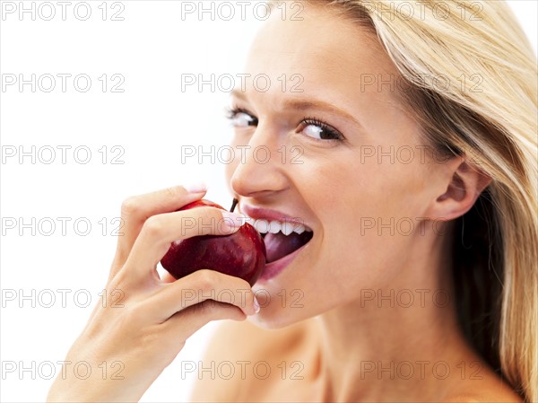 Blond woman eating an apple. Photo : momentimages