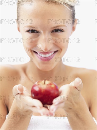 Blond woman holding an apple. Photo : momentimages