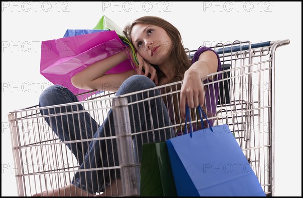 Bored woman sitting in a shopping cart with her purchases. Photo : Mike Kemp