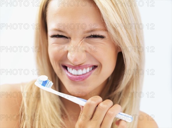 Woman about to brush her teeth. Photo : momentimages