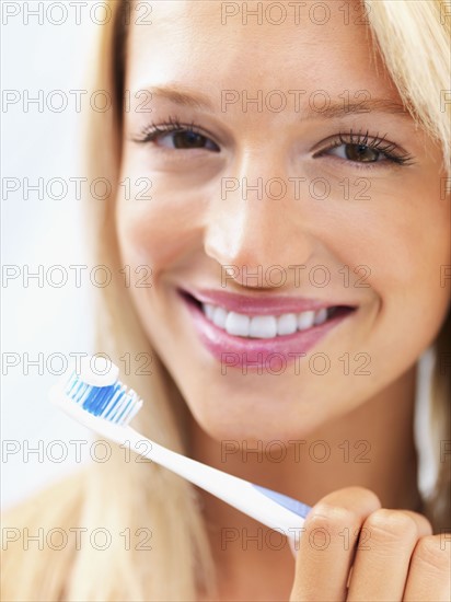 Woman holding a toothbrush. Photo : momentimages