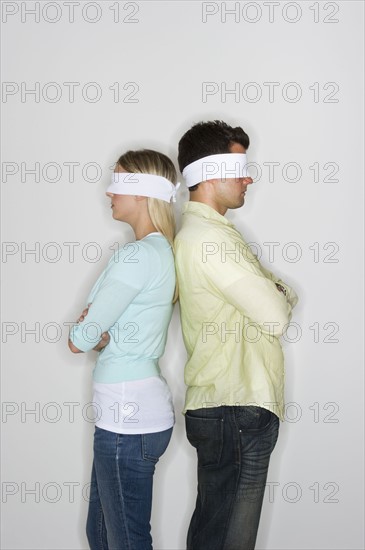 Blindfolded couple standing back to back.