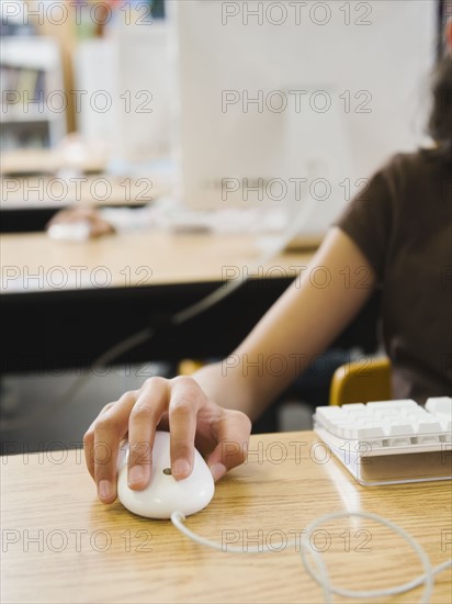 Students hand on computer mouse.