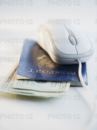 Computer mouse on top of passport and money. Photo : Jamie Grill