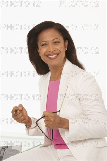 Happy businesswoman sitting on desk. Photo : K.Hatt