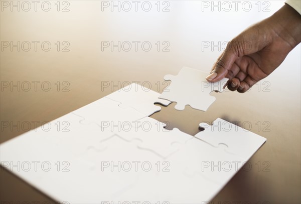 Hand putting last puzzle piece in puzzle.