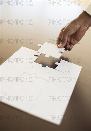 Hand putting last puzzle piece in puzzle.