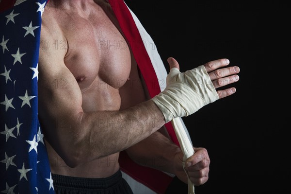 Muscular man wearing American flag as a cape. Photo : Daniel Grill