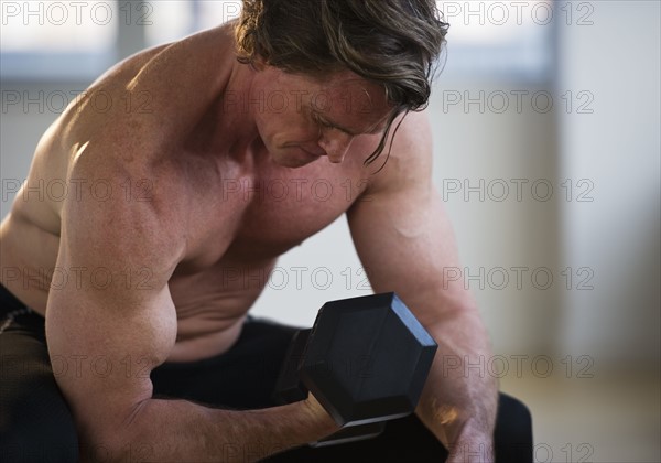 Muscular man lifting free weight. Photo : Daniel Grill