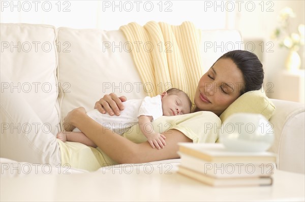 Mother and baby napping on couch.