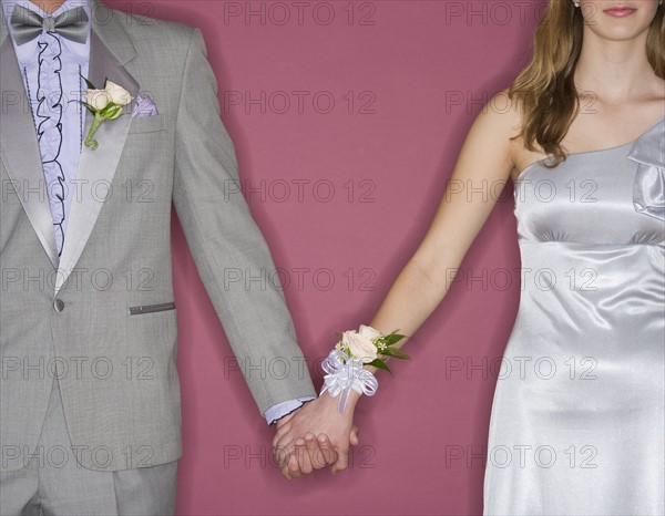 Couple in prom attire holding hands.