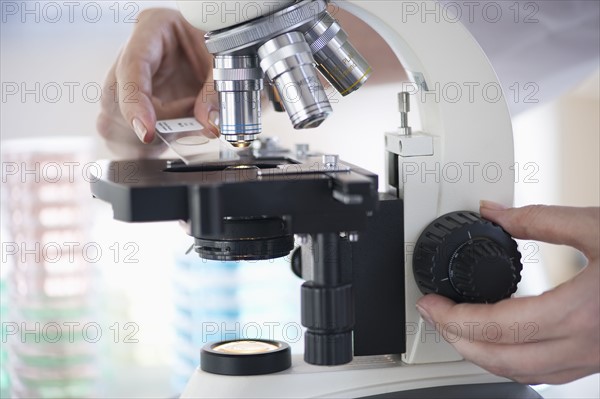 Hands on a microscope.