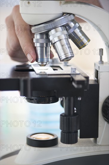 Hands on a microscope.