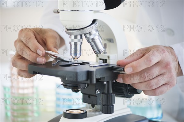 Hands on a microscope.