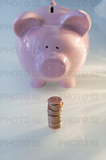 Stack of pennies in front of piggy bank.