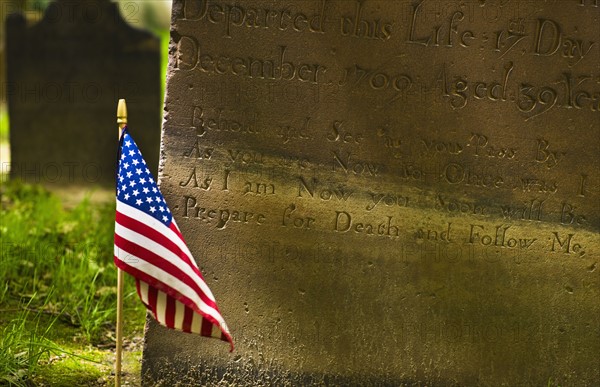 American flag in front of tombstone.