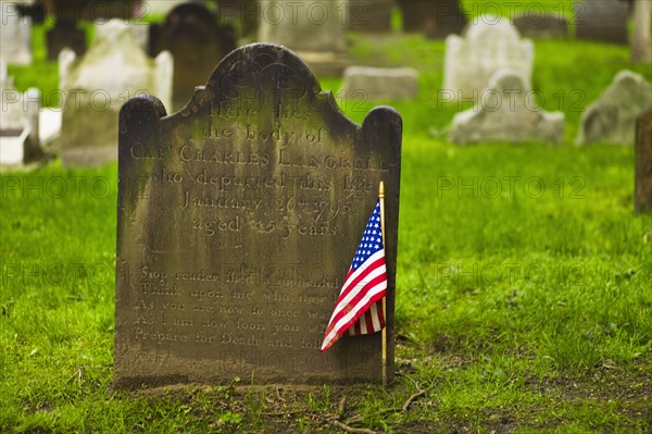 American flag in front of tombstone.