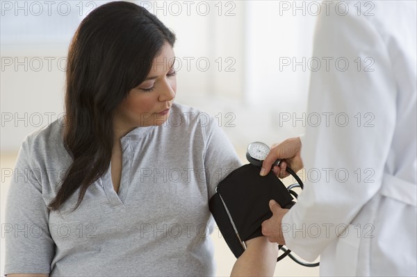 Doctor checking woman's blood pressure.