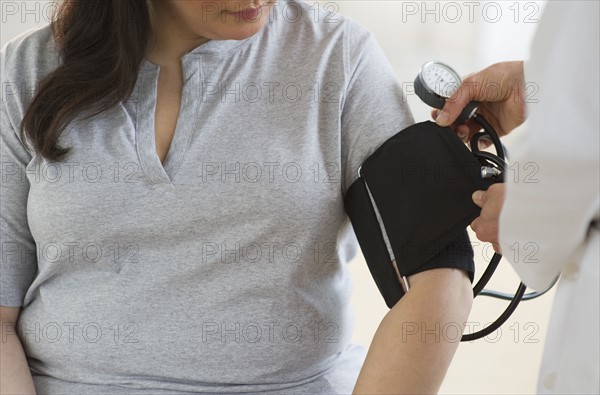 Doctor checking woman's blood pressure.