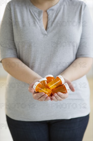 Woman holding several bottles of prescription medication.