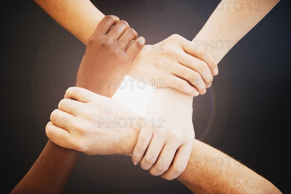 Four hands holding wrists of other people.