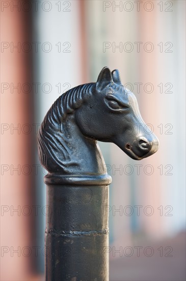 Iron statue of a horse's head on top of a post.