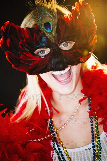 Person wearing a mardi grass mask and beads.