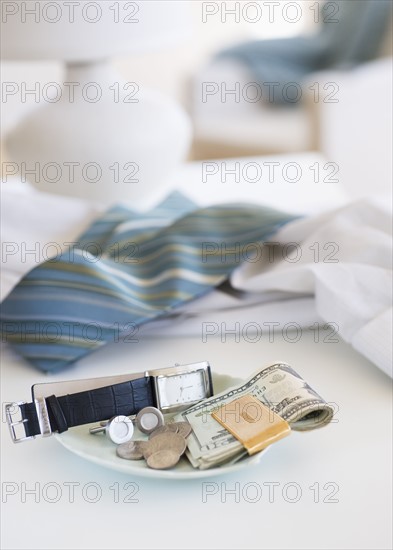 Men's items on a plate on dresser.