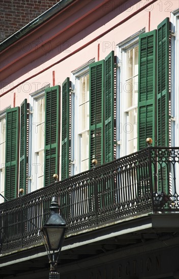 Balcony and windows with green shutters.