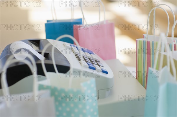 Cash register surrounded by colorful shopping bags.