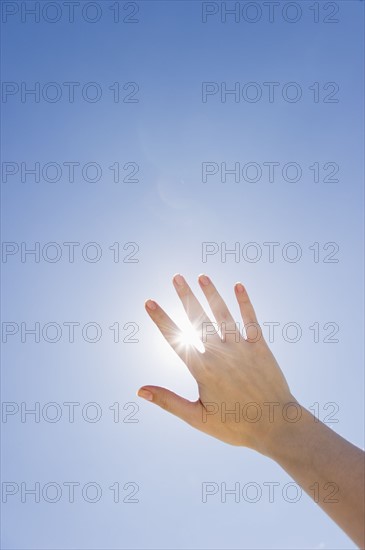 Hand held up in front of sunshine.
