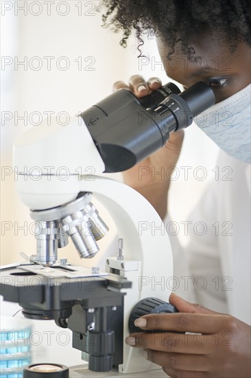 Researcher looking at specimen through microscope.