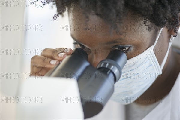 Researcher looking at specimen through microscope.