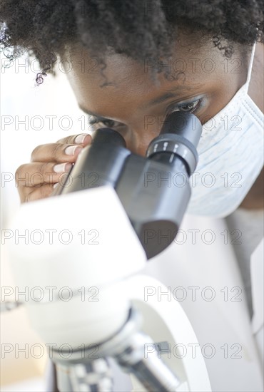 Researcher looking at specimen through microscope.