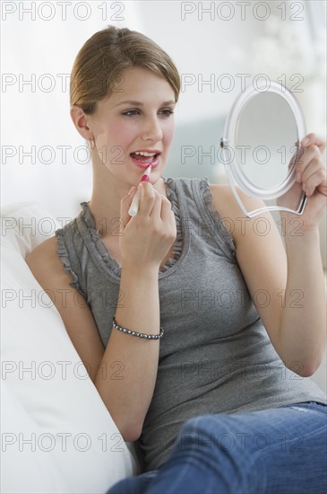 Woman putting on lipstick.