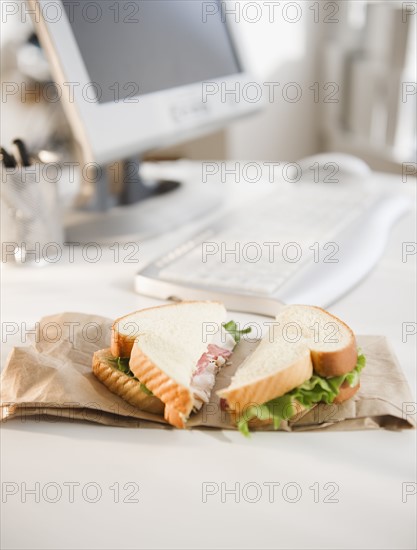 Sandwich on brown bag beside computer. Photo : Jamie Grill