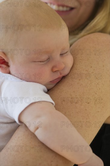 Baby sleeping in mother's arms. Photo : Chris Grill