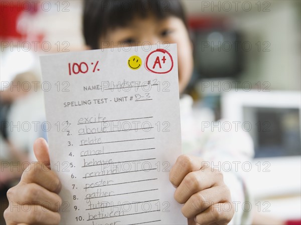 Elementary student holding an A grade paper.