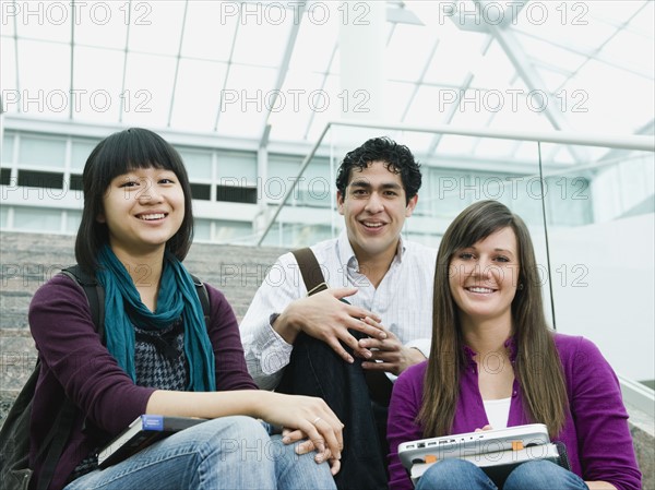 College students sitting on steps in front of library.