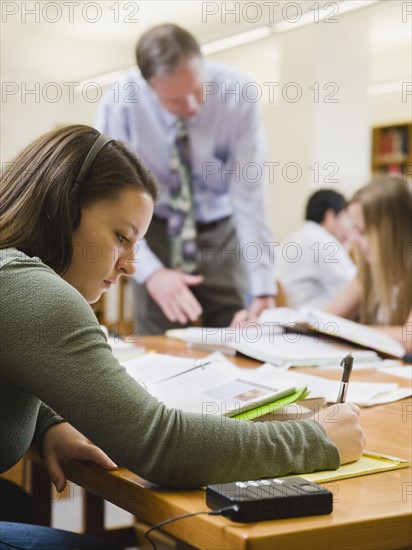 College professor helping student in library.